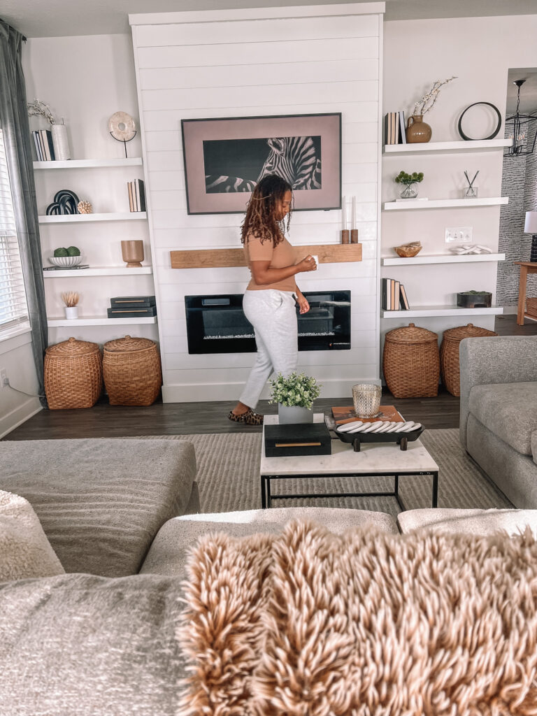 holding a mug in front of shelves